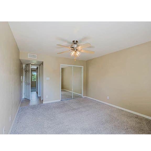 A room with a ceiling fan and carpeted floor.