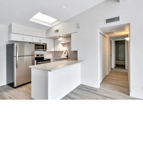 A modern kitchen with white cabinets and a stainless steel refrigerator.