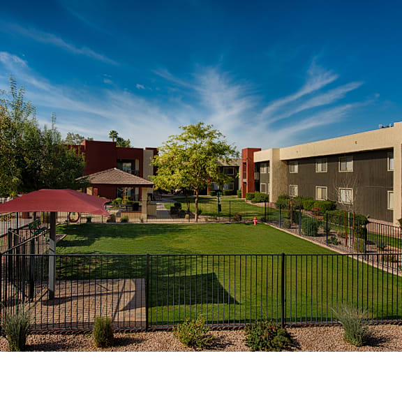 A black fence surrounds a green lawn in front of a building.