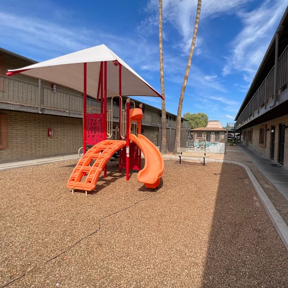 A playground with a red slide and a white canopy.