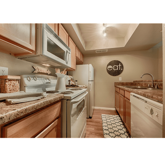 A kitchen with wooden cabinets and a sign that says "eat" on the wall.