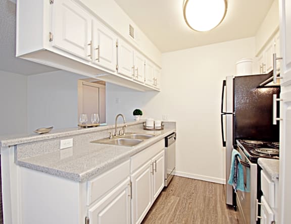 A kitchen with white cabinets and a granite countertop.