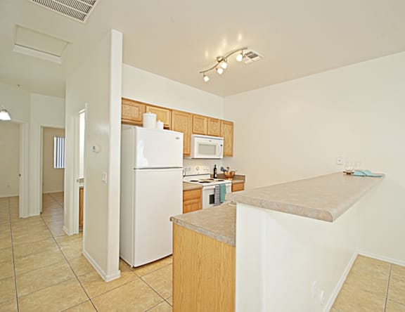 A kitchen with a white refrigerator and wooden cabinets.