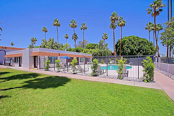 A building with a pool and palm trees in the background.