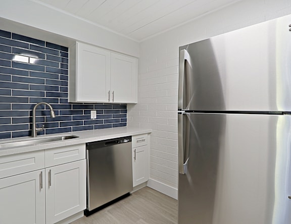 A modern kitchen with a stainless steel refrigerator and white cabinets.