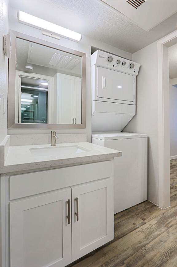 A white kitchen with a sink and a mirror.