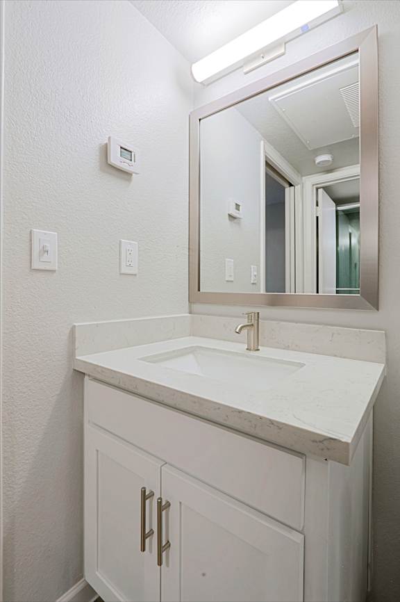 A white bathroom vanity with a sink and mirror.