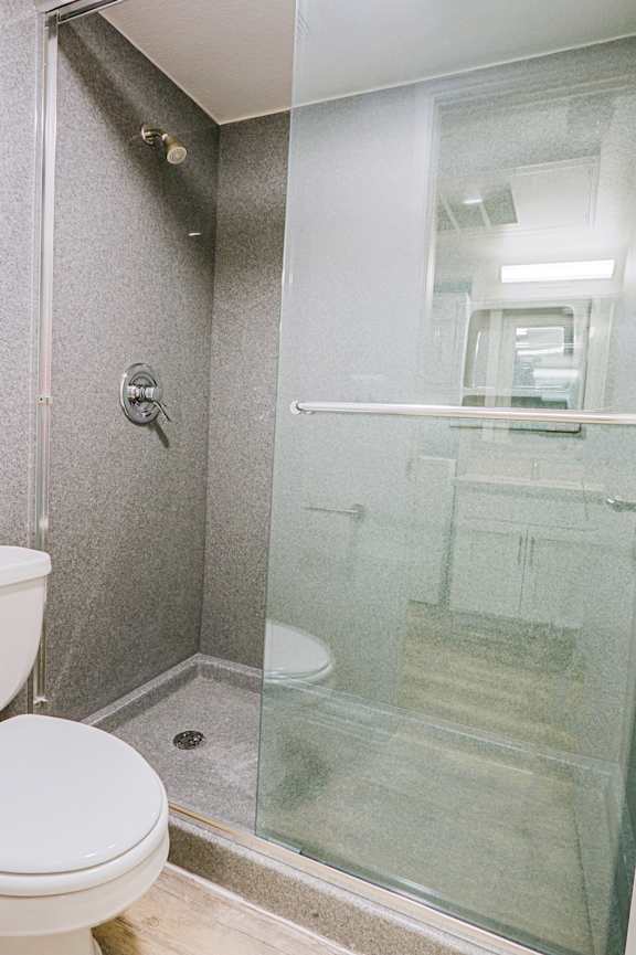 A white toilet sits next to a walk-in shower.