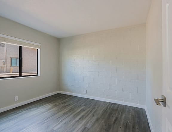 A room with a white brick wall and wooden flooring.
