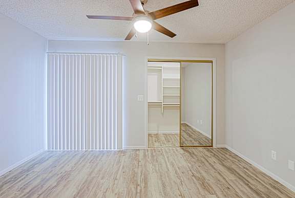 A room with a ceiling fan and a wooden floor.