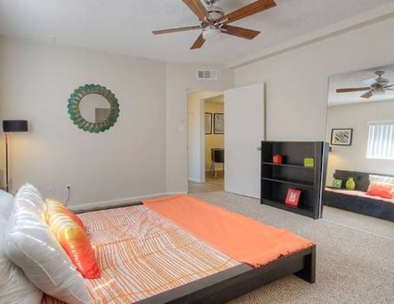A bedroom with a bed, a ceiling fan, and a wreath on the wall.