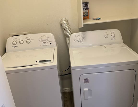 Two white front loading washing machines in a small laundry room.