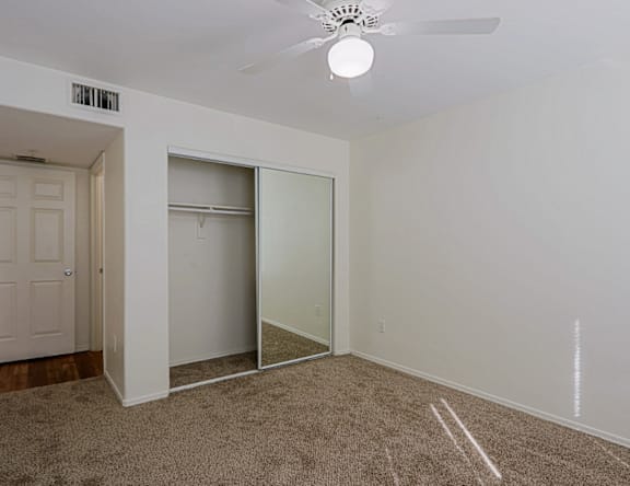 A room with a carpeted floor and a ceiling fan.