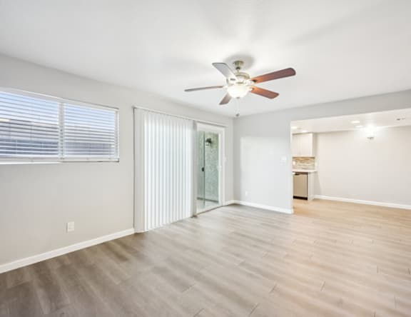 A room with a ceiling fan and sliding glass doors.