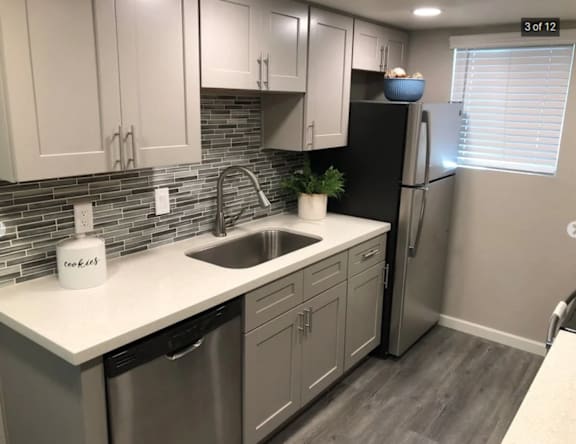 A kitchen with a black refrigerator and white countertops.