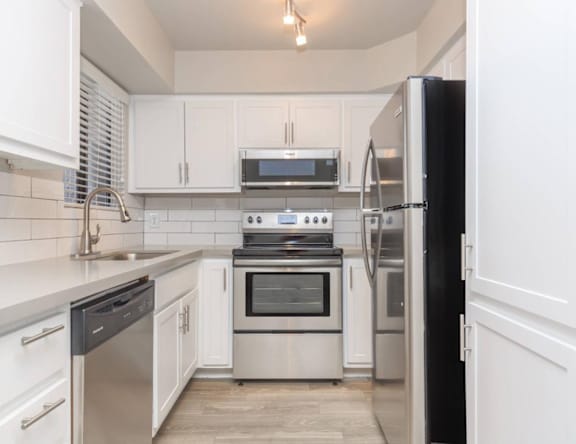 A modern kitchen with white cabinets and stainless steel appliances.
