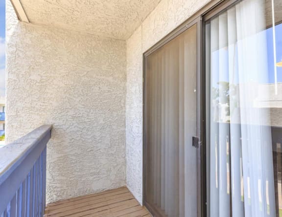 A balcony with a glass door and a wooden floor.