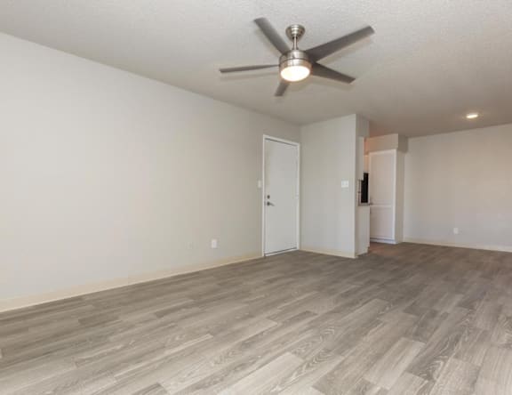 A room with a ceiling fan and light fixture, and a wooden floor.