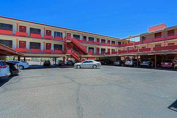 A parking lot with cars and a building with red stairs.