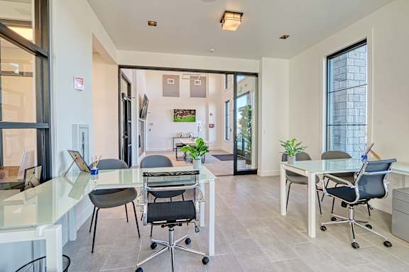 A modern office space with glass walls and a variety of chairs and tables.