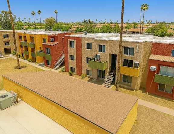 A row of multi-colored apartment buildings with a palm tree in the background.