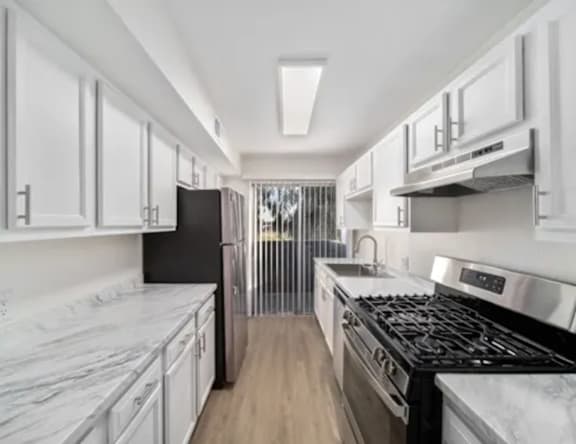 A modern kitchen with white cabinets and a black refrigerator.