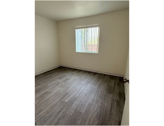A room with a window and wooden flooring.