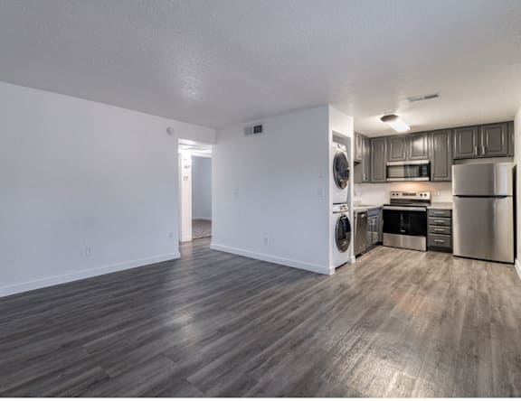 A spacious kitchen with stainless steel appliances and wooden flooring.
