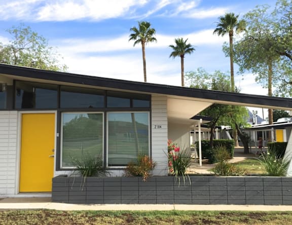 A modern house with a yellow door and glass windows.