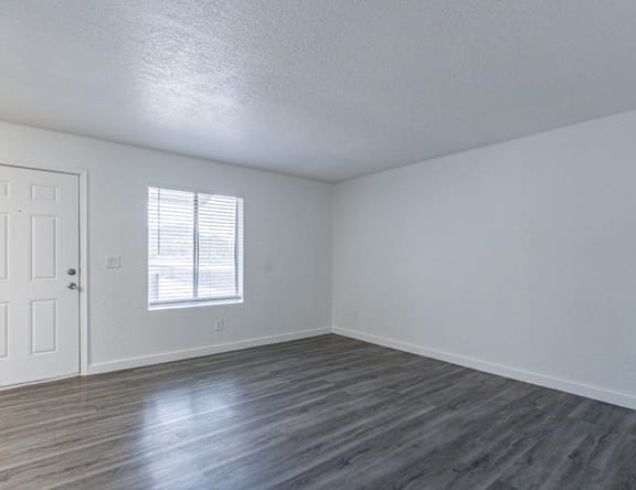 A room with a wooden floor and a window with blinds.