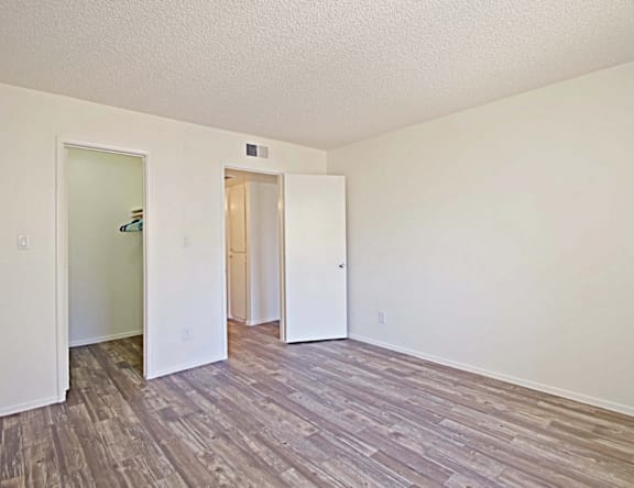 A room with a white ceiling, two doors, and a wooden floor.
