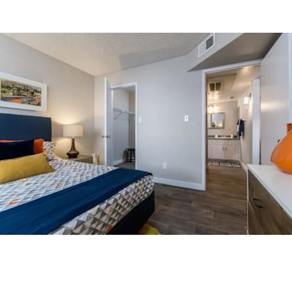 A bedroom with a bed, a lamp, and a painting on the wall.