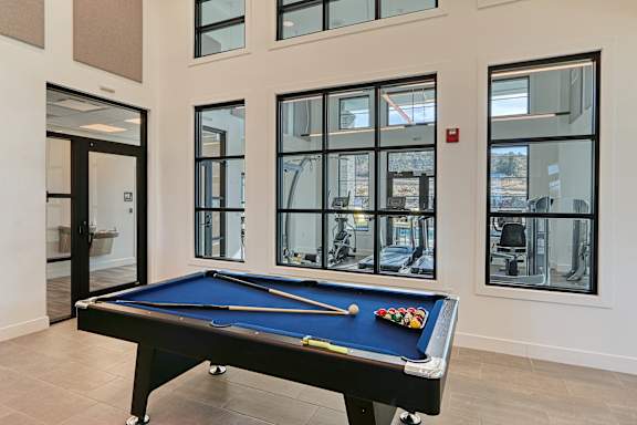 A pool table with a blue cloth and a pool cue in the middle.