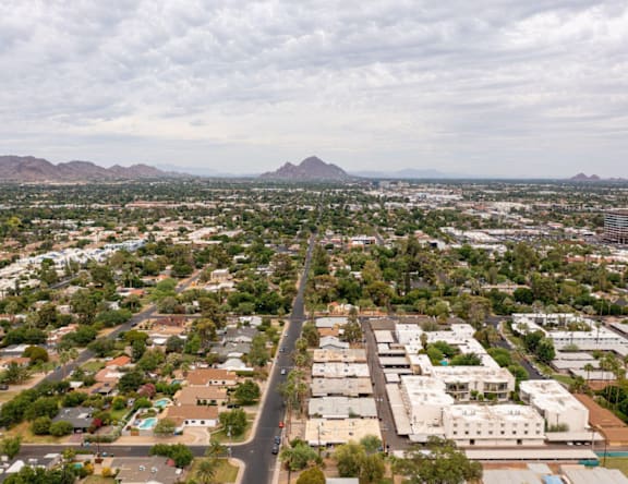A road cuts through a residential area with a mountain in the distance.