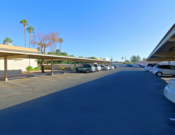 A parking lot with cars parked and a building on the left.