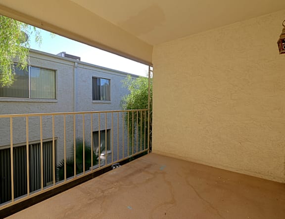 A balcony with a metal railing and a building in the background.