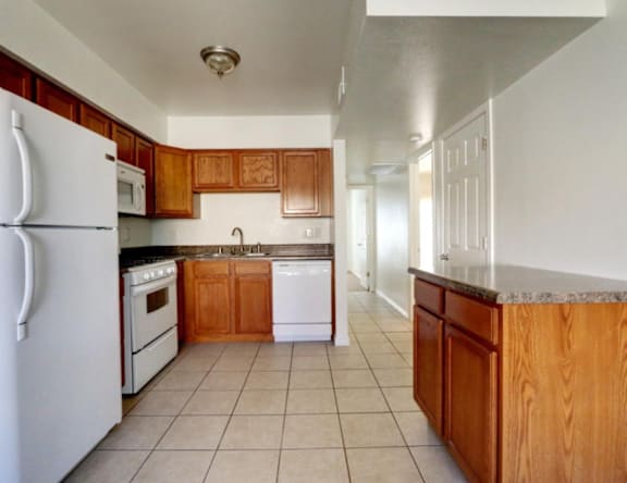 A kitchen with white appliances and wooden cabinets.