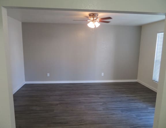 A room with a ceiling fan and wooden flooring.