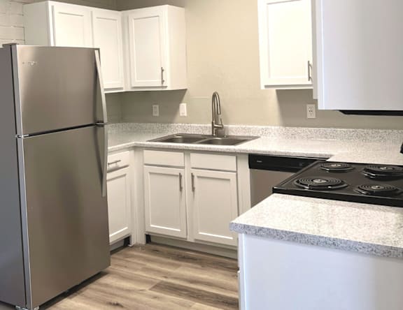 A kitchen with a stainless steel refrigerator and white cabinets.