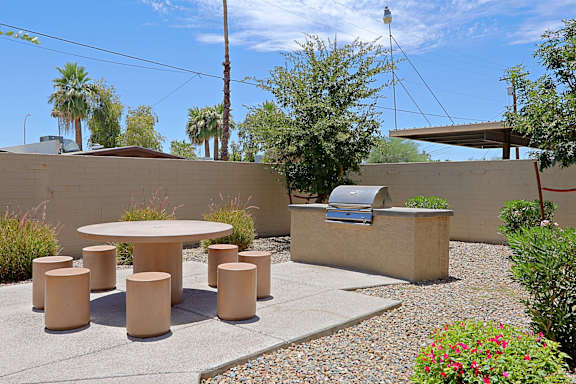A patio with a table, chairs and plants.