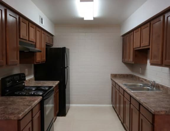 A kitchen with brown cabinets and a black refrigerator.