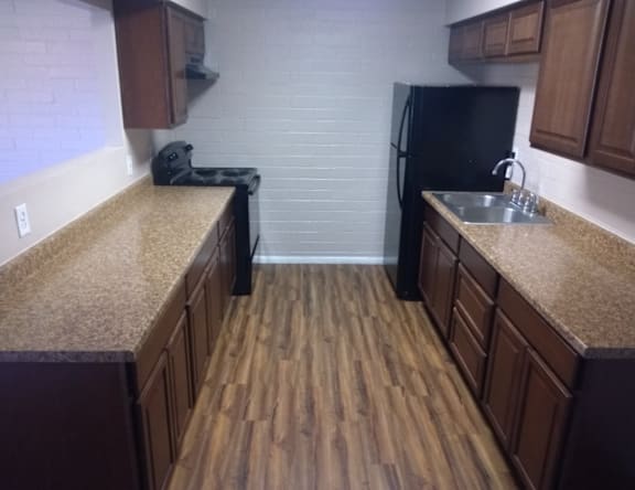 A kitchen with wooden floors and a black refrigerator.