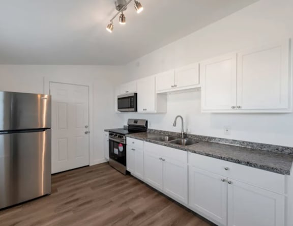 A kitchen with white cabinets and a granite countertop.