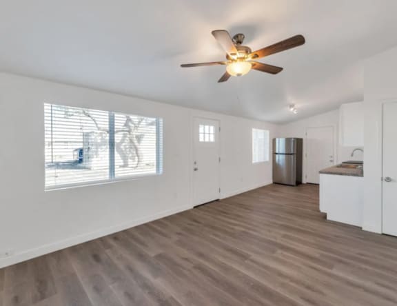 A room with a ceiling fan and wooden flooring.