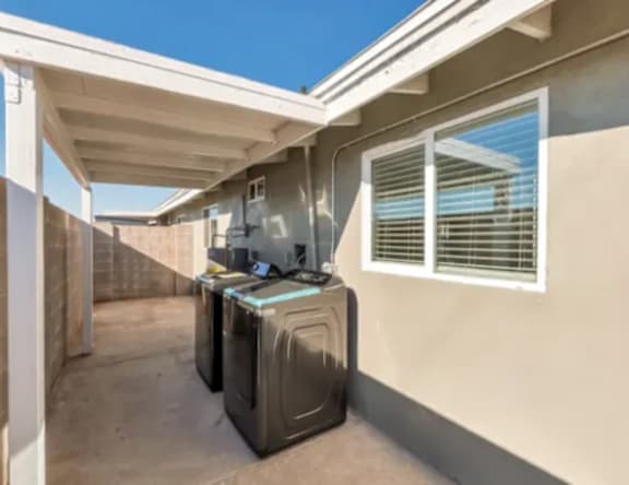 A washing machine is placed on the balcony of a house.