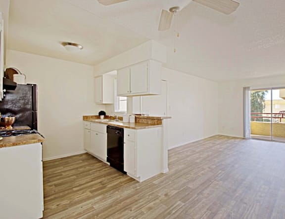 A kitchen with white cabinets and a wooden floor.