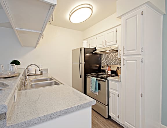 A kitchen with a sink, stove, and refrigerator.