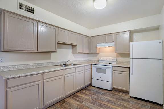 A kitchen with white appliances and wooden cabinets.