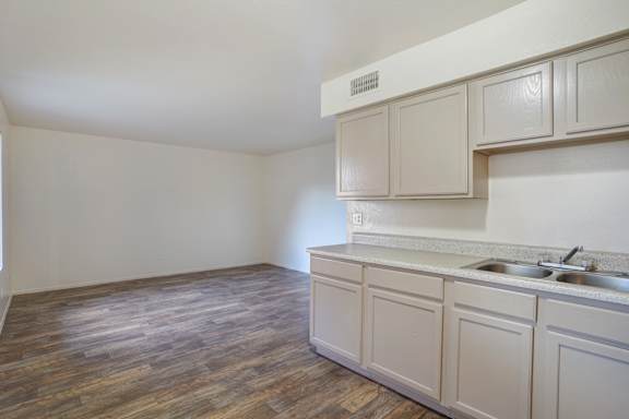 A kitchen with wooden floors and white cabinets.