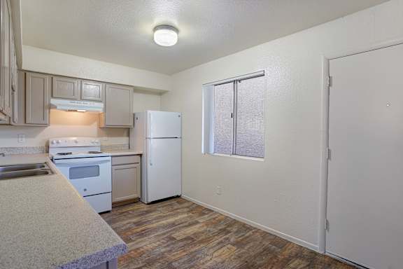 A kitchen with a refrigerator, stove, and sink.
